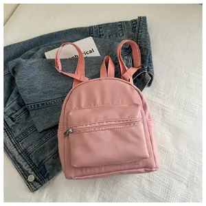 Detalle de mochila pequeña rosa de nailon impermeable con bolsillo frontal con cremallera