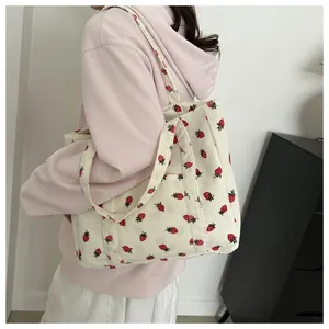 Detail van gebroken witte corduroy shopper met aardbeienprint en brede schouderriem