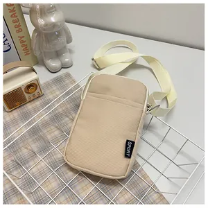 Detail der beigen Cord-Handytasche mit SPORT-Label und verstellbarem Gurt