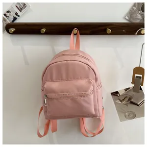 Detalle de la mini mochila rosa que muestra la textura de nailon y bolsillo frontal