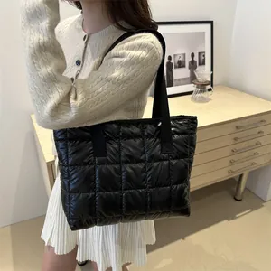Grand sac fourre-tout noir matelassé brillant porté par un mannequin en tenue décontractée
