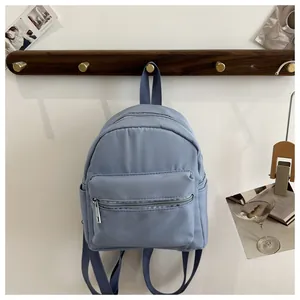 Primer plano de mochila azul claro impermeable con varios bolsillos en gancho de madera