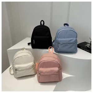 Mini mochilas impermeables en varios colores sobre pedestales blancos en un estudio