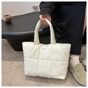 Gros plan d'un sac cabas matelassé beige crème avec motif à carreaux et bouton pression