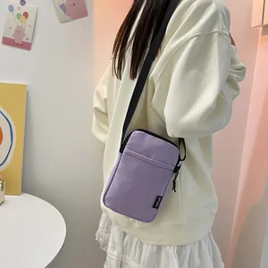 Violette Nylon-Handytasche mit verstellbarem Gurt und Sport-Tag am Model gezeigt