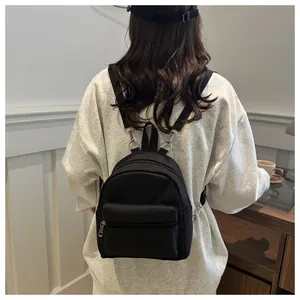 Mini mochila de nailon negro con cremalleras metálicas plateadas mostrada en un modelo