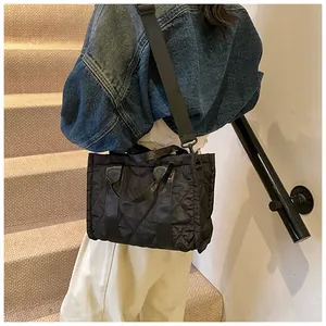 Close-up of black quilted nylon tote bag with detachable strap worn by model