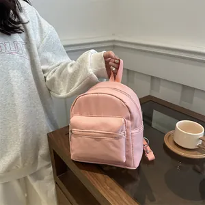 Mini mochila de nailon rosa con múltiples bolsillos en mesa de madera con café