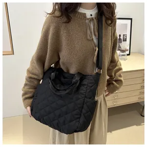Woman carrying a black diamond quilted tote bag with adjustable shoulder strap