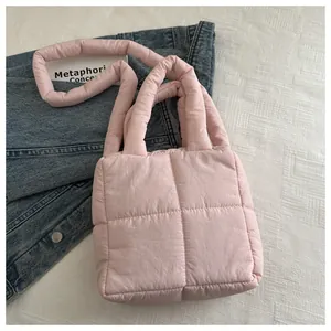 Détail d'un sac à main matelassé rose clair avec poignées rembourrées sur textile