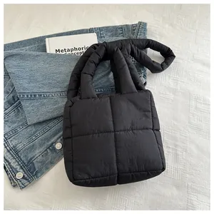 Vue détaillée du sac cabas matelassé noir sur tissu texturé blanc avec accessoires