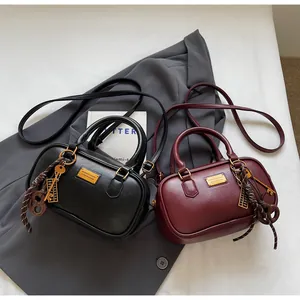 Detail der Vintage-Bowling-Handtaschen in Schwarz und Burgund mit goldenen Abakus-Anhängern