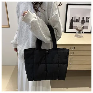 Détail du sac cabas matelassé noir avec fermeture par bouton pression et texture douce
