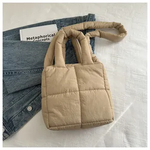 Détail de la texture du sac matelassé beige sur tissu blanc avec des livres