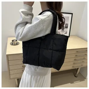 Vue détaillée du cabas en nylon matelassé noir avec coutures à carreaux et bouton pression