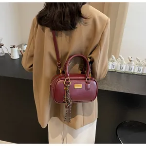 Detailansicht der weinroten Retro-Henkeltasche mit goldenen Beschlägen und Anhänger