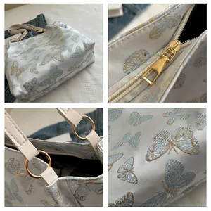 Close-up of butterfly embroidery detail and gold zipper on a white tote bag