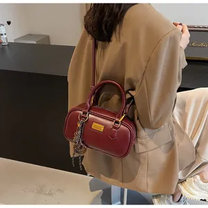 Detailansicht der burgunderroten Vintage-Bowling-Tasche mit goldener Hardware und Anhänger