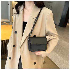 Close-up of a black matte leather crossbody bag with a designer chain strap on a blazer