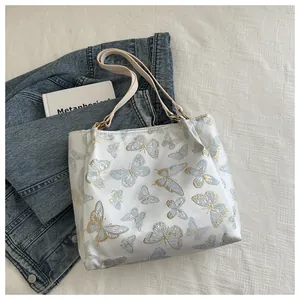 Detailed butterfly embroidery on a white canvas tote bag with a golden and blue pattern