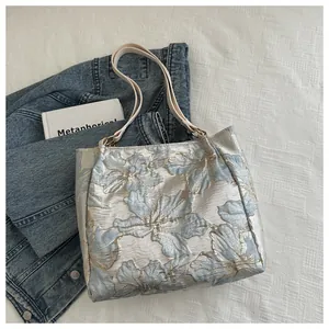 Close-up of light blue floral jacquard fabric and faux leather straps on a tote bag