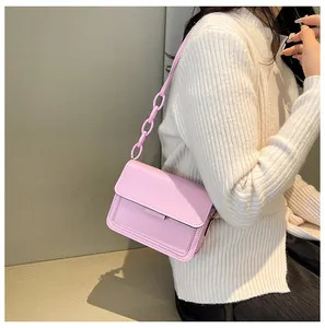Pink crossbody bag with pebble leather texture and decorative resin chain strap details