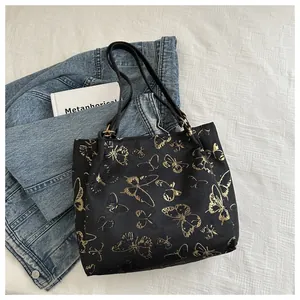Detailed close-up of golden butterfly embroidery on durable black canvas tote bag