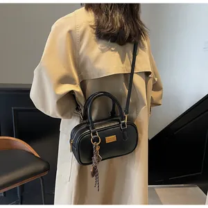 Detailaufnahme der schwarzen Boston-Tasche mit Goldplakette und Web-Anhänger
