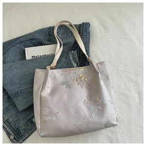 Detail of purple satin tote bag featuring intricate floral and butterfly embroidery