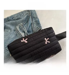 Detail showing puffer style makeup bag with pink flower embroidery and black zipper