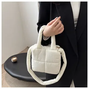 Détail du sac à main matelassé blanc avec bandoulière bouffante sur fond de blazer noir