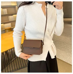 Detail view of a vintage brown leather crossbody bag worn on the waist by a model
