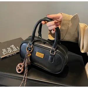 Detail der schwarzen Bowling-Tasche mit goldenen Beschlägen und Flechtanhänger