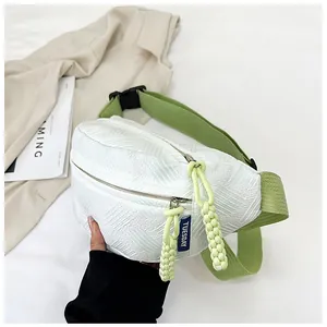 Detail der weißen Brusttasche mit grünem Gurt und gelbgrünen gewebten Reißverschluss-Zügen