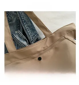 Detailed close-up of khaki tote bag with double stitching and black metal snap button