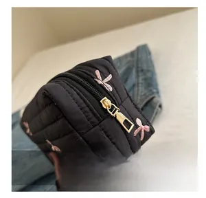 Detail showing high-quality smooth gold metal zipper on black quilted embroidered pouch