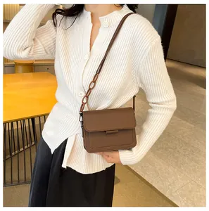 Brown leather crossbody square bag styled with white cardigan and black skirt for women