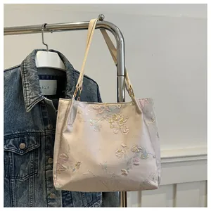Detailed view of floral jacquard tote bag with golden hardware and slim leather strap