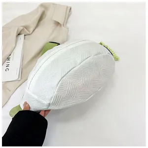 Detail der weißen geprägten Crossbody-Tasche mit grünem Knoten und gewebtem Schultergurt