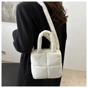 Gros plan sur un sac matelassé blanc avec poignée rembourrée et texture en duvet