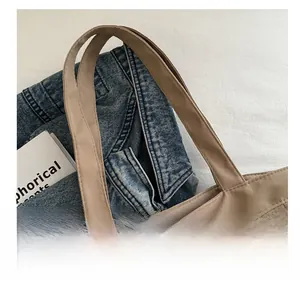 Detail showing wide handles and fine stitching on the khaki nylon tote bag