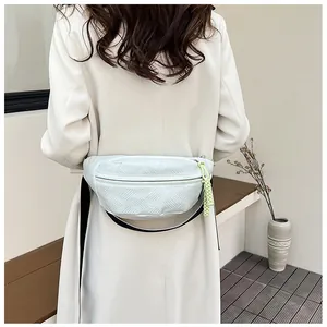 Detail der weißen gesteppten Brusttasche mit grünem Reißverschluss-Anhänger und Gurt