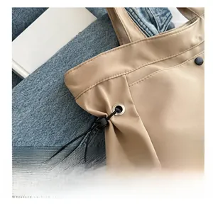 Detailed close-up of khaki tote bag showing black drawstring buckle and fine stitching