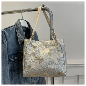 Close-up of elegant floral jacquard pattern and gold metal hardware on tote bag