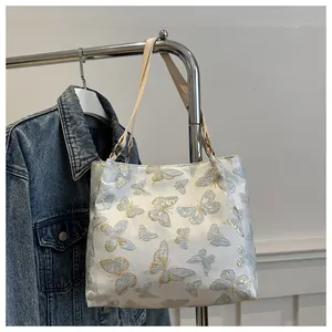 Close-up of elegant butterfly embroidery and ivory leather strap on a large tote bag