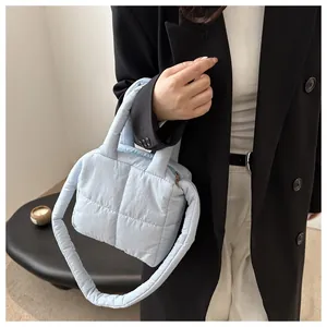 Détail du sac matelassé bleu clair avec poignées rembourrées et fermeture éclair en métal