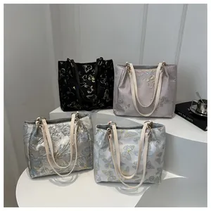 Detail of embroidered tote bags with floral butterfly patterns on display stands