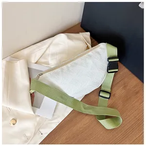 Detailansicht der weißen Brusttasche mit grünem Nylonriemen auf dem Holztisch