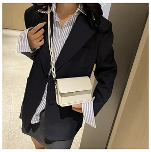 Detail of minimalist cream square shoulder bag with large resin chain link and flap closure