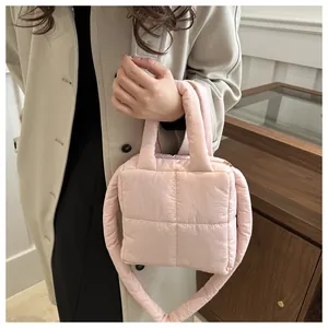 Détail d'un sac à main matelassé rose élégant porté par un mannequin en trench-coat